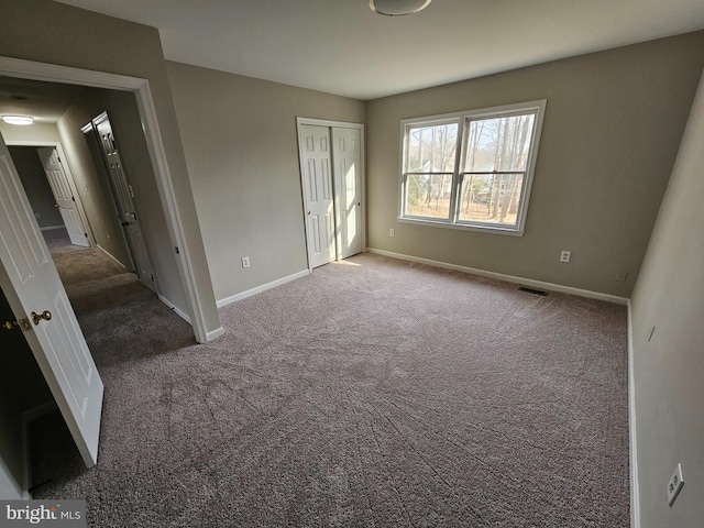 unfurnished bedroom with a closet and dark colored carpet