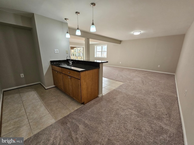 kitchen with pendant lighting, light colored carpet, kitchen peninsula, and sink