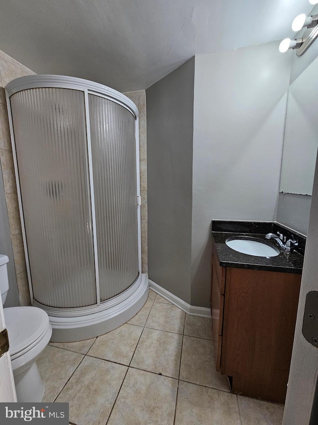 bathroom featuring tile patterned flooring, vanity, toilet, and a shower with shower door