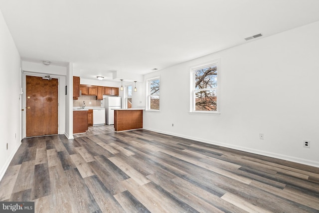 unfurnished living room featuring sink and dark hardwood / wood-style flooring