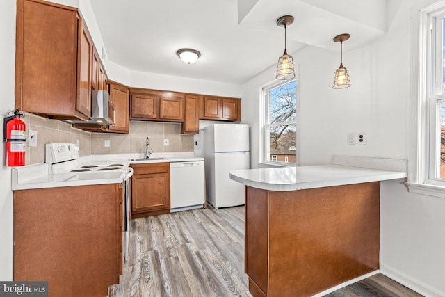 kitchen featuring pendant lighting, sink, white appliances, backsplash, and kitchen peninsula