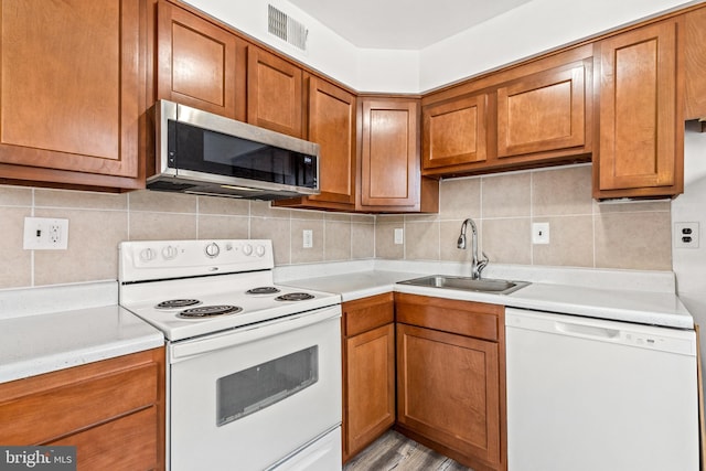 kitchen featuring white appliances, sink, and backsplash