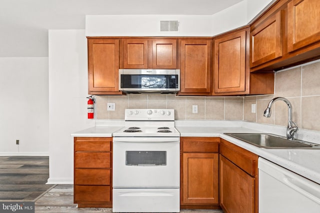 kitchen with sink, white appliances, dark wood-type flooring, and decorative backsplash