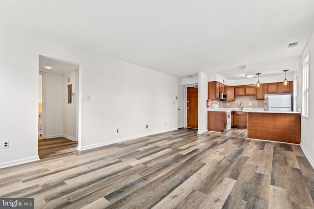 kitchen featuring pendant lighting, white appliances, hardwood / wood-style floors, and decorative backsplash