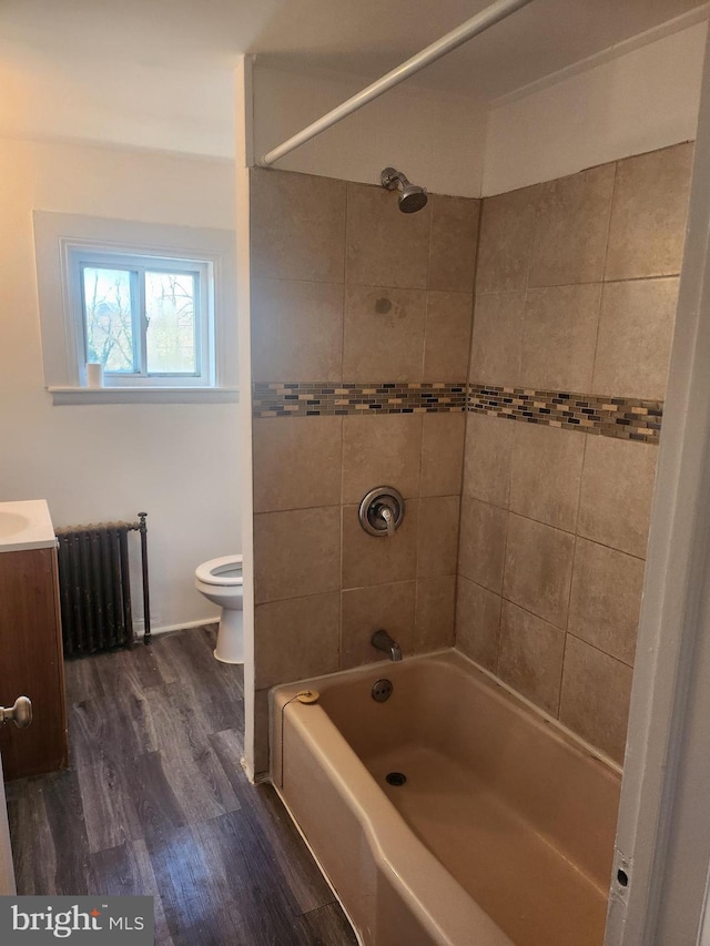 full bathroom featuring tiled shower / bath, radiator heating unit, wood-type flooring, vanity, and toilet