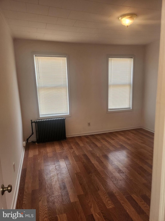 unfurnished room with dark hardwood / wood-style floors and radiator heating unit