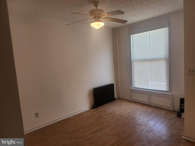 spare room with wood-type flooring, radiator heating unit, a textured ceiling, and ceiling fan