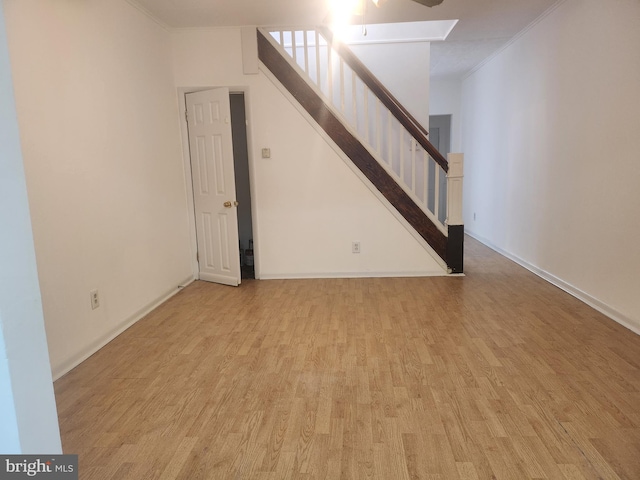 unfurnished living room featuring ornamental molding and light wood-type flooring