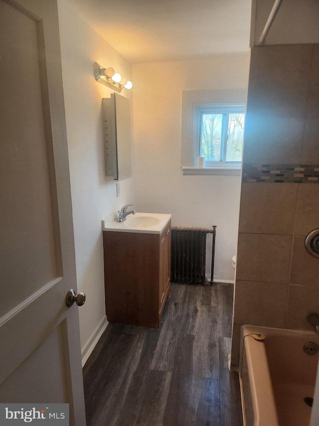 bathroom featuring hardwood / wood-style flooring, vanity, radiator heating unit, and washtub / shower combination