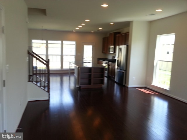 kitchen featuring dark countertops, plenty of natural light, stainless steel appliances, and dark wood-type flooring