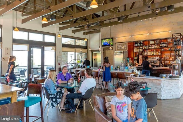 dining area featuring beam ceiling, a towering ceiling, and track lighting