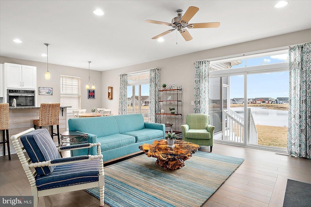 living room featuring a water view, ceiling fan, and light hardwood / wood-style floors