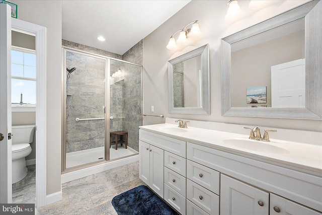 bathroom featuring vanity, a shower with shower door, and toilet