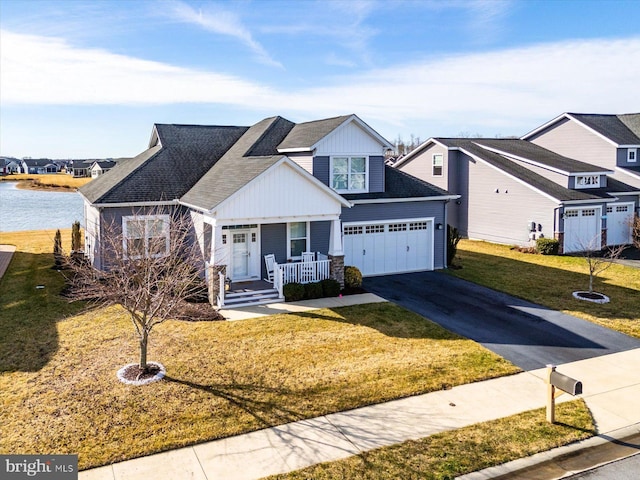 view of front of home featuring a garage, a front yard, a water view, and a porch