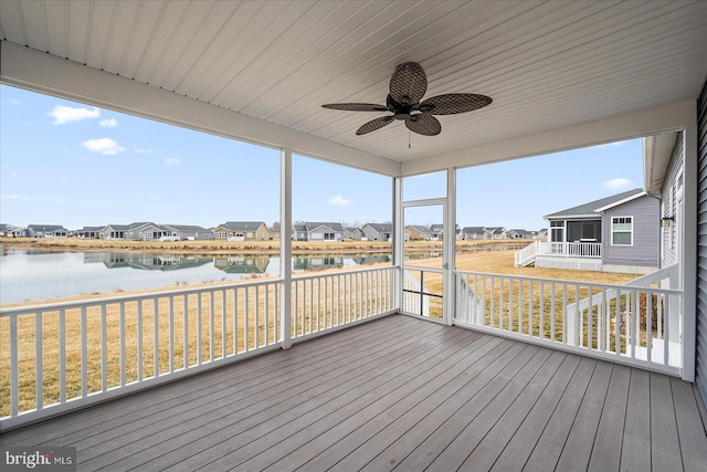 unfurnished sunroom featuring ceiling fan and a water view