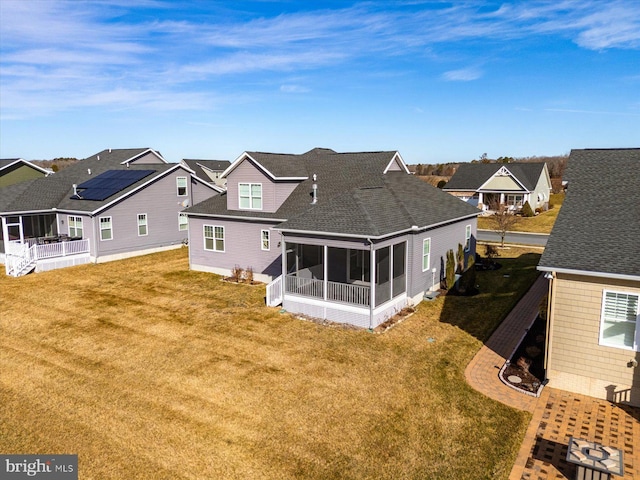 back of property featuring a sunroom and a lawn