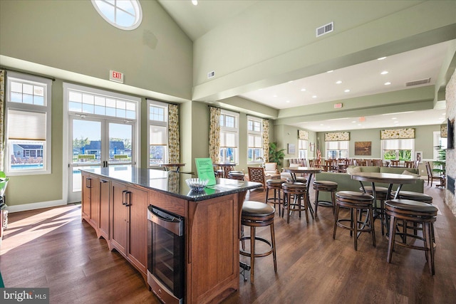 kitchen featuring a kitchen island, dark stone countertops, wine cooler, dark wood-type flooring, and french doors