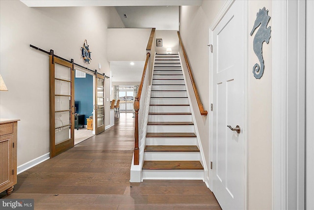 staircase featuring wood-type flooring and a barn door