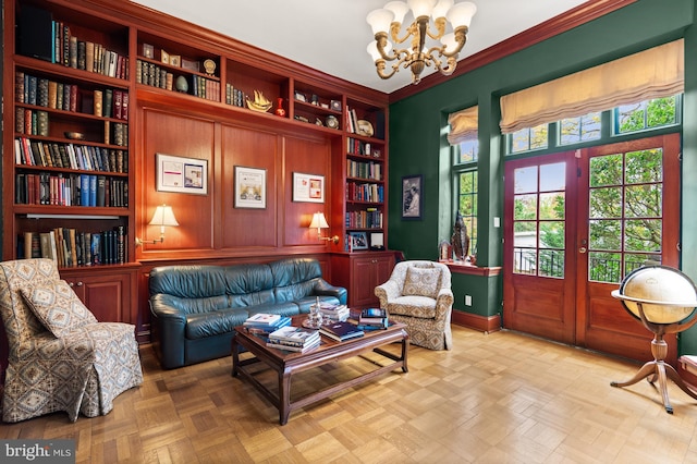 sitting room featuring ornamental molding, french doors, a notable chandelier, and built in shelves