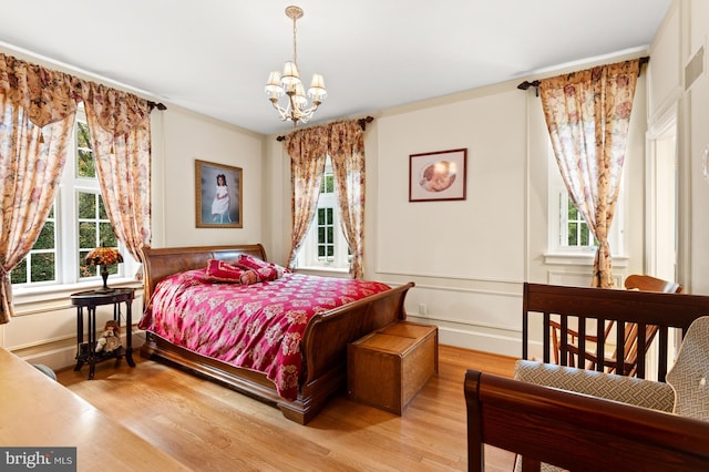 bedroom with an inviting chandelier, multiple windows, and wood finished floors