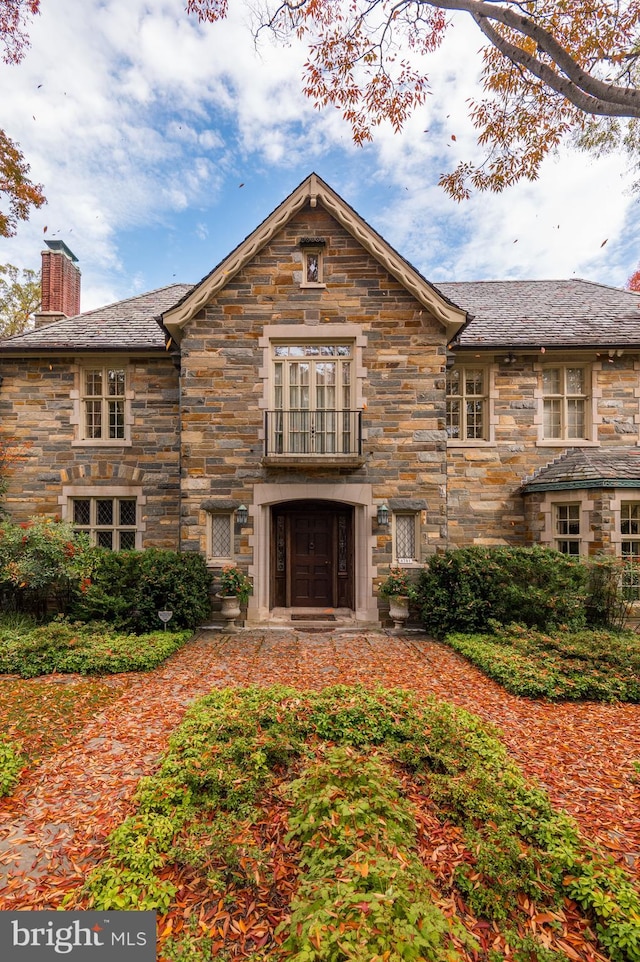 view of front of house featuring stone siding and a chimney