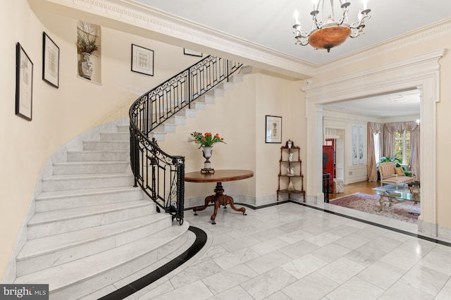 foyer entrance with marble finish floor, baseboards, a chandelier, and crown molding