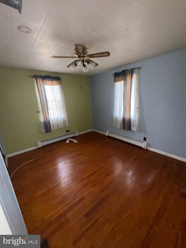 spare room with hardwood / wood-style floors, ceiling fan, and baseboard heating