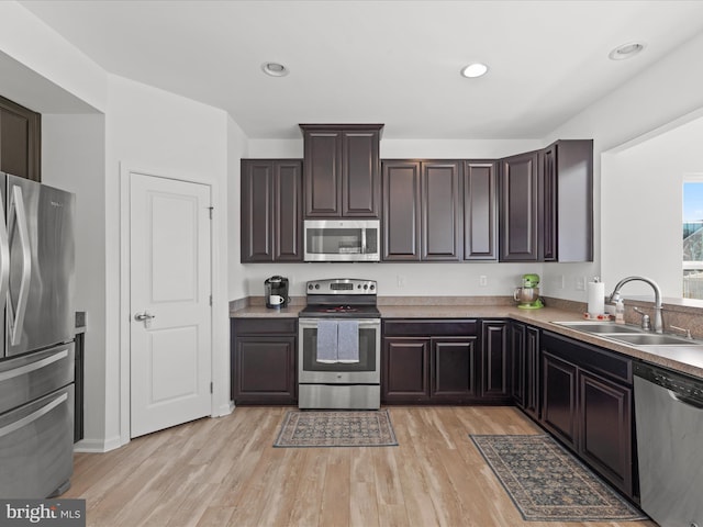 kitchen with stainless steel appliances, sink, dark brown cabinetry, and light hardwood / wood-style flooring