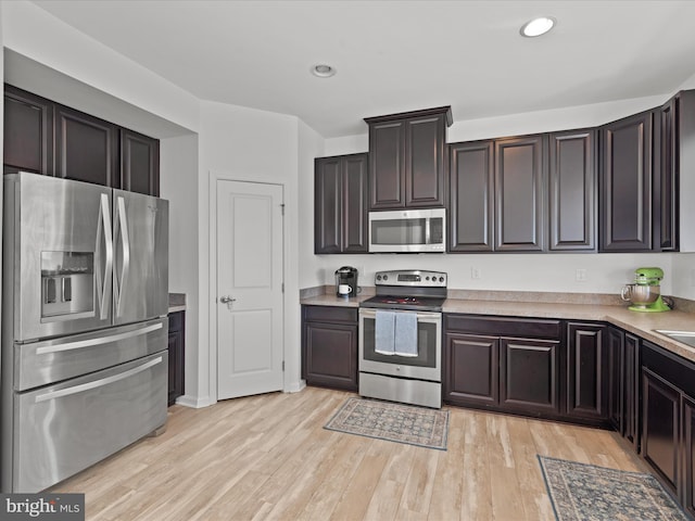 kitchen with dark brown cabinetry, light hardwood / wood-style flooring, and appliances with stainless steel finishes