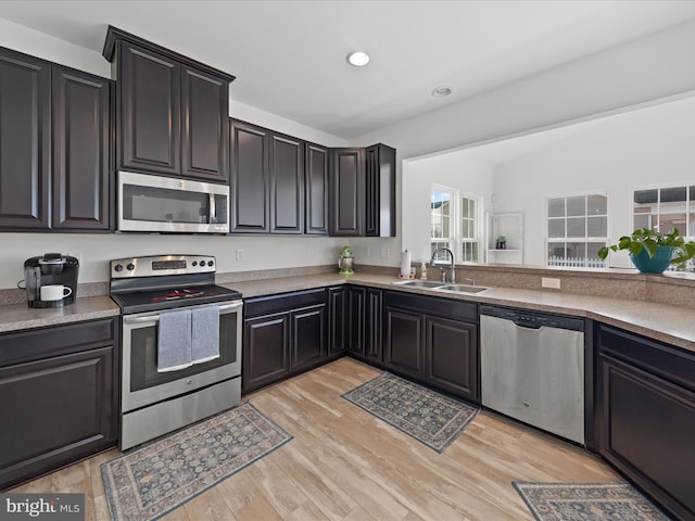 kitchen with appliances with stainless steel finishes, sink, and light hardwood / wood-style flooring