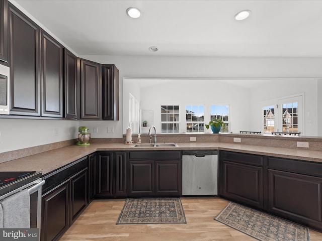 kitchen featuring lofted ceiling, sink, appliances with stainless steel finishes, dark brown cabinetry, and light wood-type flooring