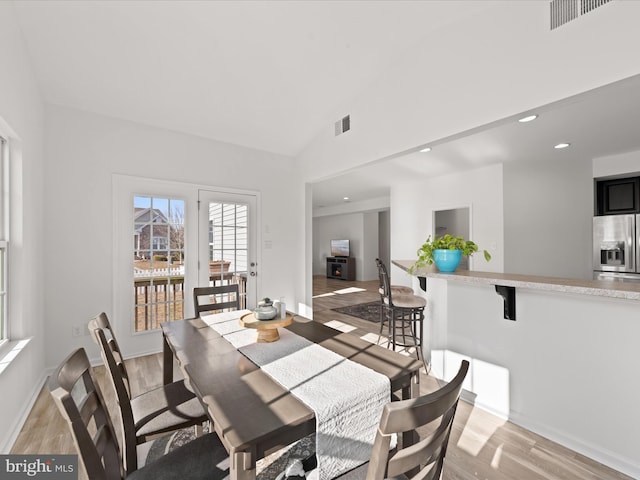 dining space with vaulted ceiling and light wood-type flooring