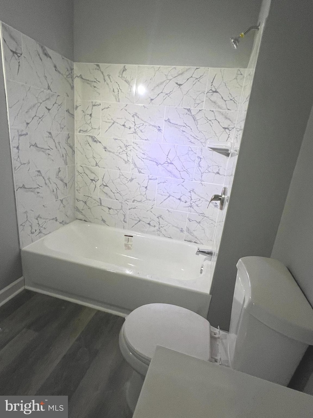 bathroom featuring tiled shower / bath, wood-type flooring, and toilet