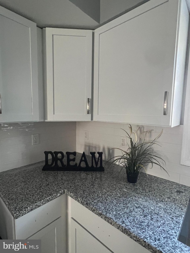 kitchen with white cabinetry, stone countertops, and backsplash