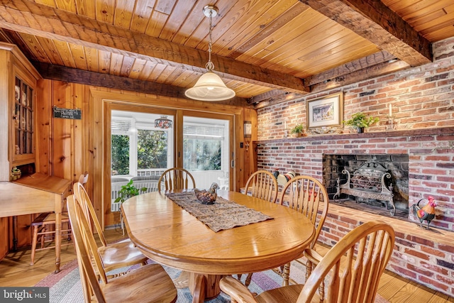 dining room with beamed ceiling, wood walls, wood ceiling, and light hardwood / wood-style flooring