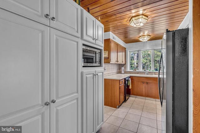 kitchen with tasteful backsplash, white cabinetry, sink, light tile patterned floors, and black appliances