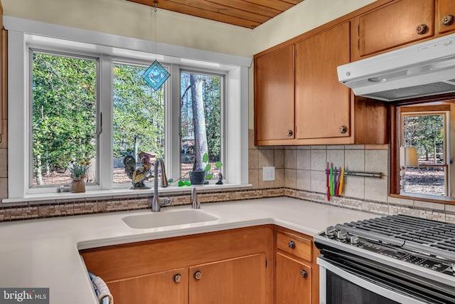 kitchen with hanging light fixtures, gas stove, sink, and tasteful backsplash