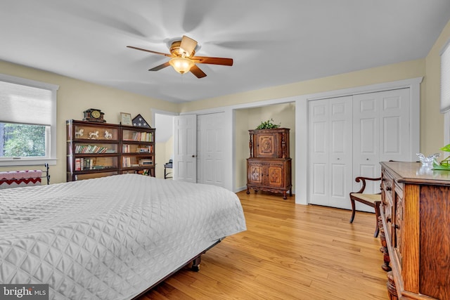 bedroom with ceiling fan, two closets, and light hardwood / wood-style floors