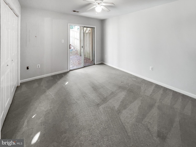 unfurnished room with ceiling fan and dark carpet