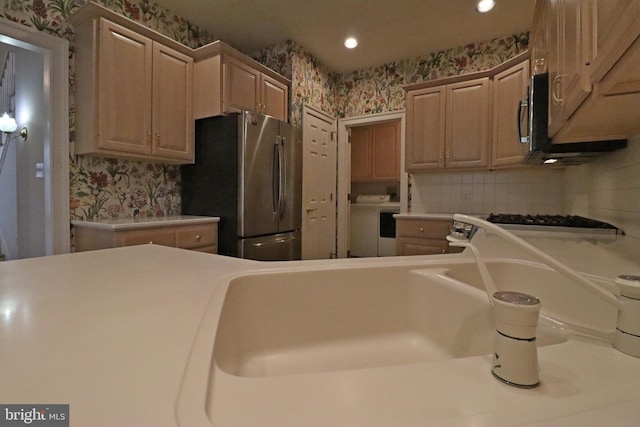 kitchen featuring light brown cabinetry, washer / dryer, and stainless steel appliances