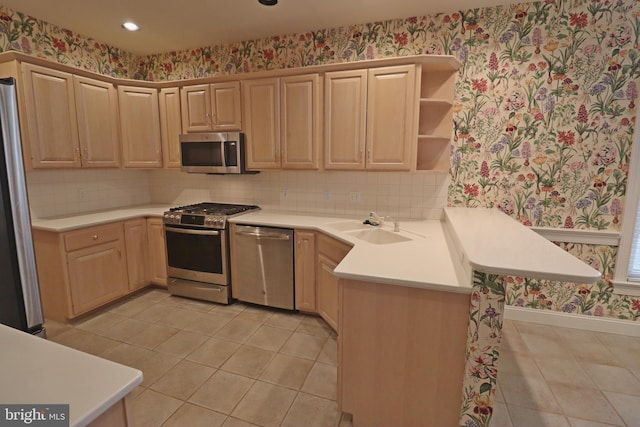 kitchen with stainless steel appliances, light brown cabinetry, kitchen peninsula, and sink