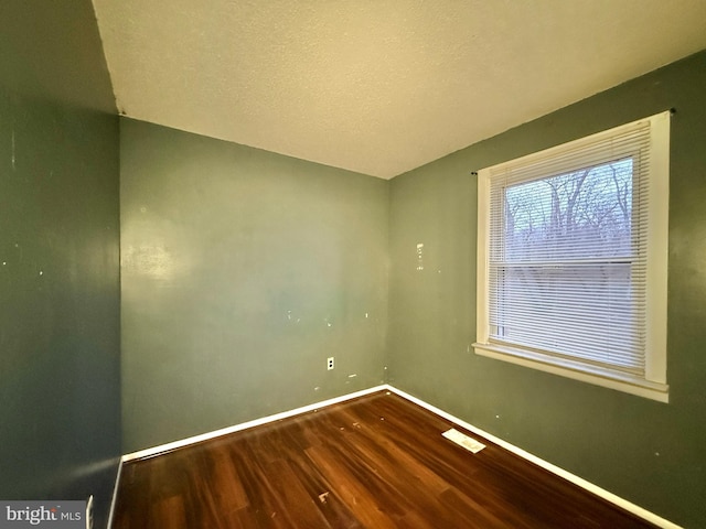 empty room with hardwood / wood-style floors and a textured ceiling