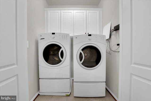 washroom featuring cabinets, washer and dryer, and light tile patterned floors