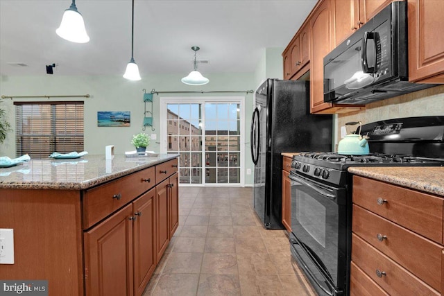 kitchen with hanging light fixtures, light stone countertops, a center island, and black appliances