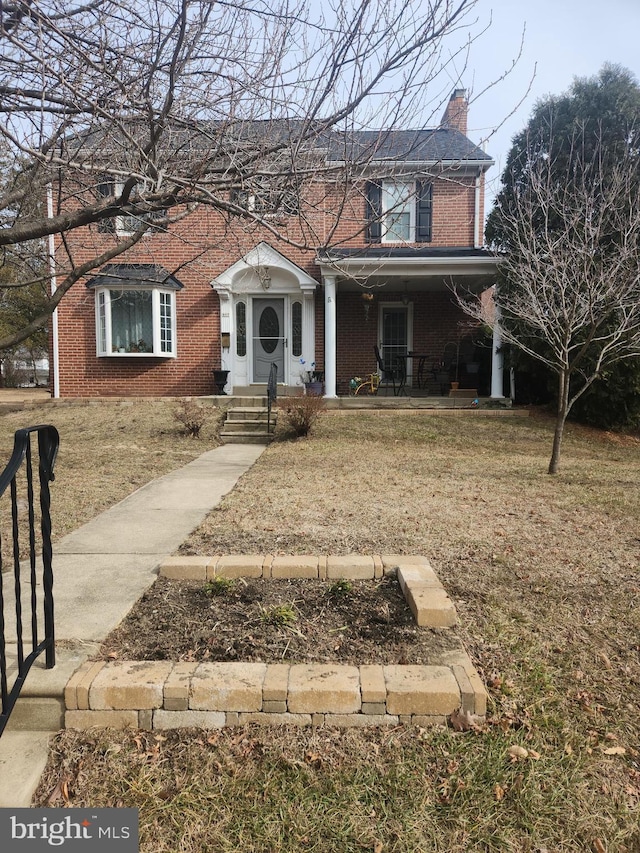 view of front facade featuring a front yard, a chimney, and brick siding