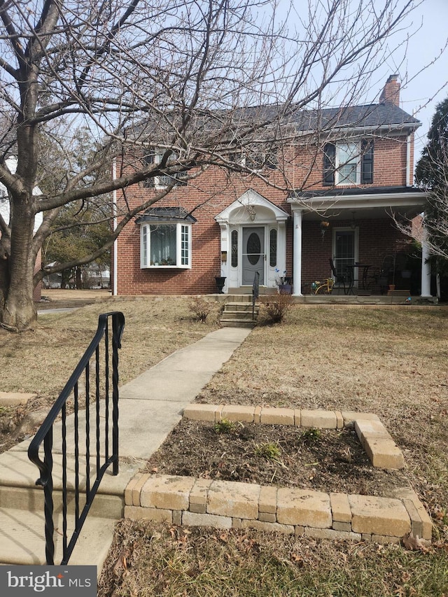 view of front facade featuring a chimney, a front lawn, and brick siding