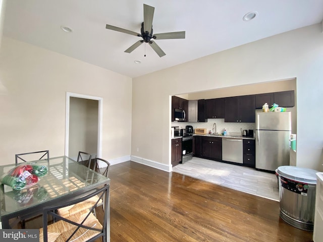 kitchen featuring sink, appliances with stainless steel finishes, dark brown cabinetry, decorative backsplash, and light wood-type flooring