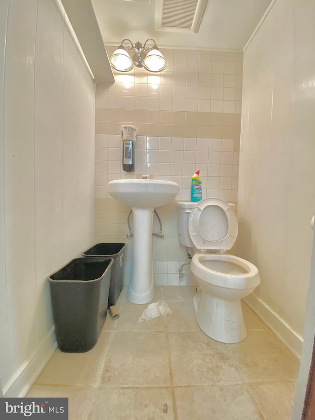 bathroom with tile patterned flooring, tile walls, and toilet