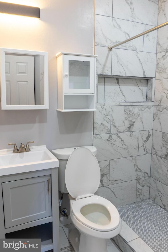 bathroom featuring vanity, toilet, and a tile shower