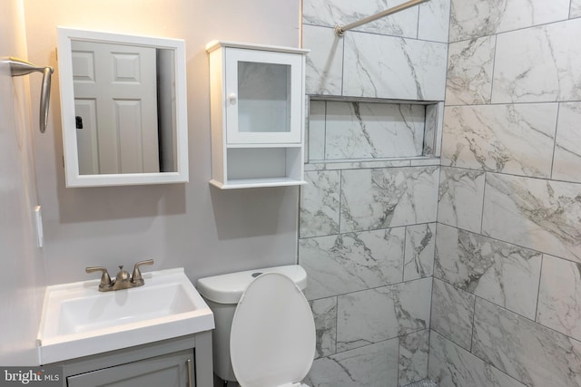 bathroom featuring vanity, tiled shower, and toilet